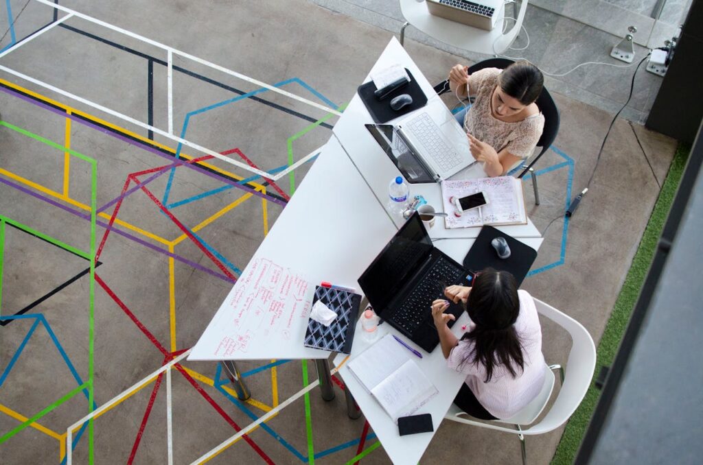 Two Women Sitting in Chairs Using Laptop Computers